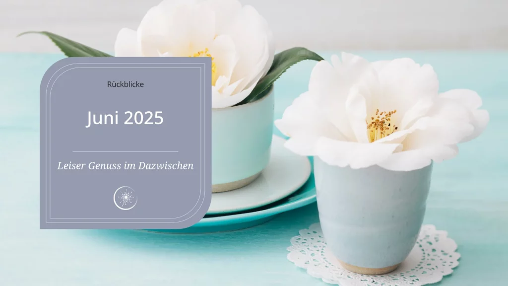Juni 2025 - ein Becher und eine Tasse stehen auf einem Tisch. In beiden ist eine weiße Wildrosenblüte