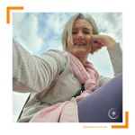 Frau sitzt vor einen hellen Himmel und macht ein Selfie.