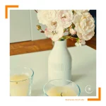 Wildrosen in einer Vase vor zwei Glaskerzen