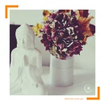 Ein Trockenblumenstrauß hinter einer kleinen Buddhastatue