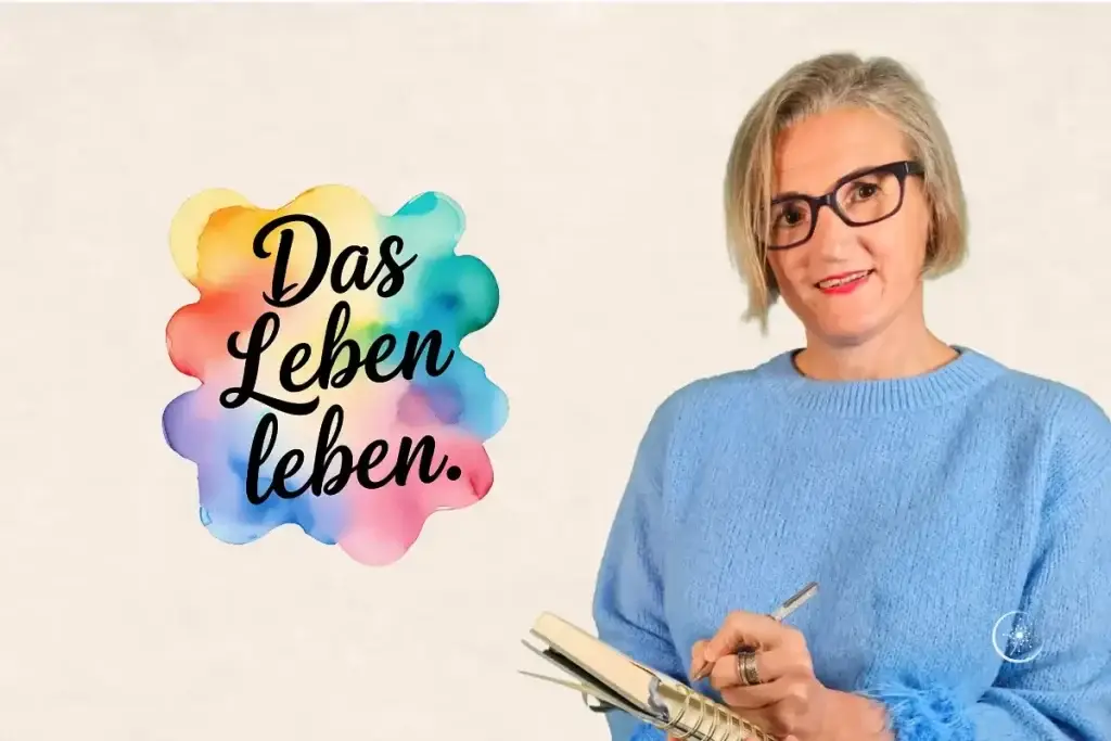 Jahresmotto Depression - Stefanie Koch steht mit Heft und Schreiber vor einer hellen Wand mit dem bunten Schriftzug "Das Leben leben"