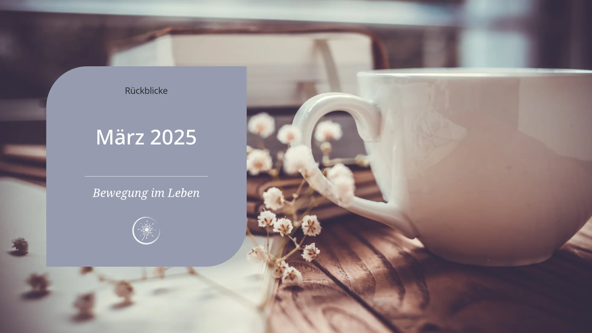 März 2025 - eine weiße Keramiktasse steht vor einem Stabel Bücher auf einem Holztisch