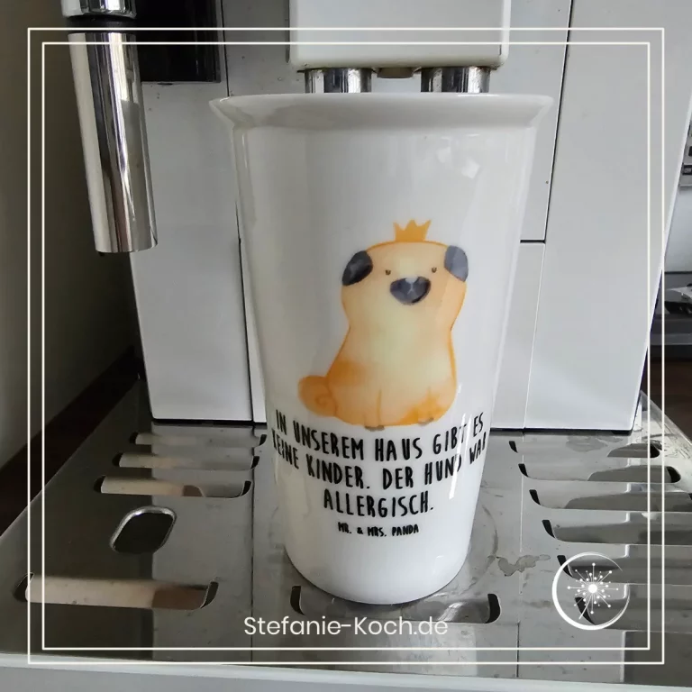 Ein Becher mit einer Mops-Zeichnung darauf steht in einem Kaffeevollautomat