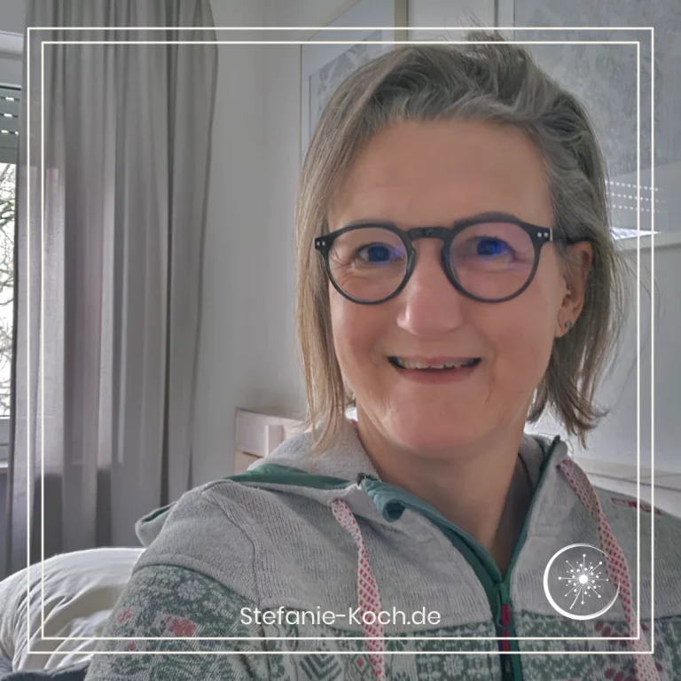 Portraitaufnahme einer lächelnden Frau mit Brille und unordentlichen Haaren