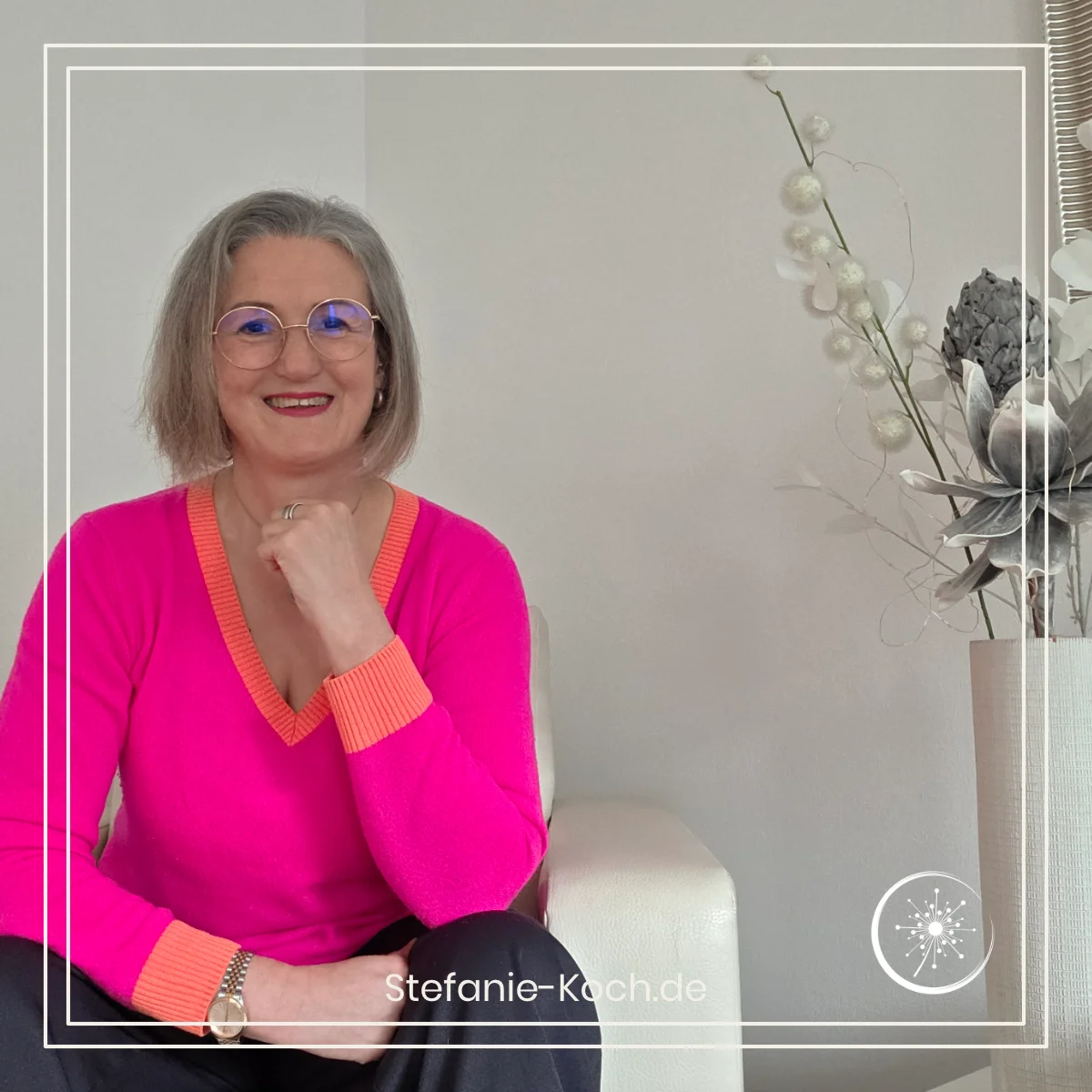 Frau sitzt auf einem Sessel und schaut in die Kamera.