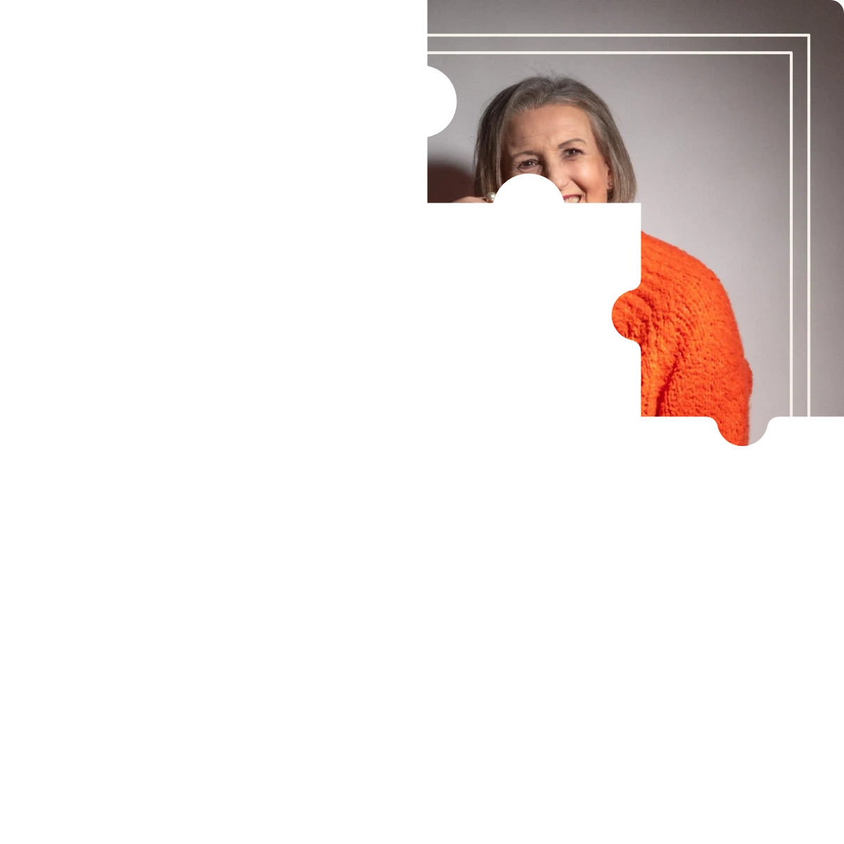 Puzzleteil eines Bildes - Frau sitzt in Jeans und orangefarbenen Pullover auf dem Fußboden.