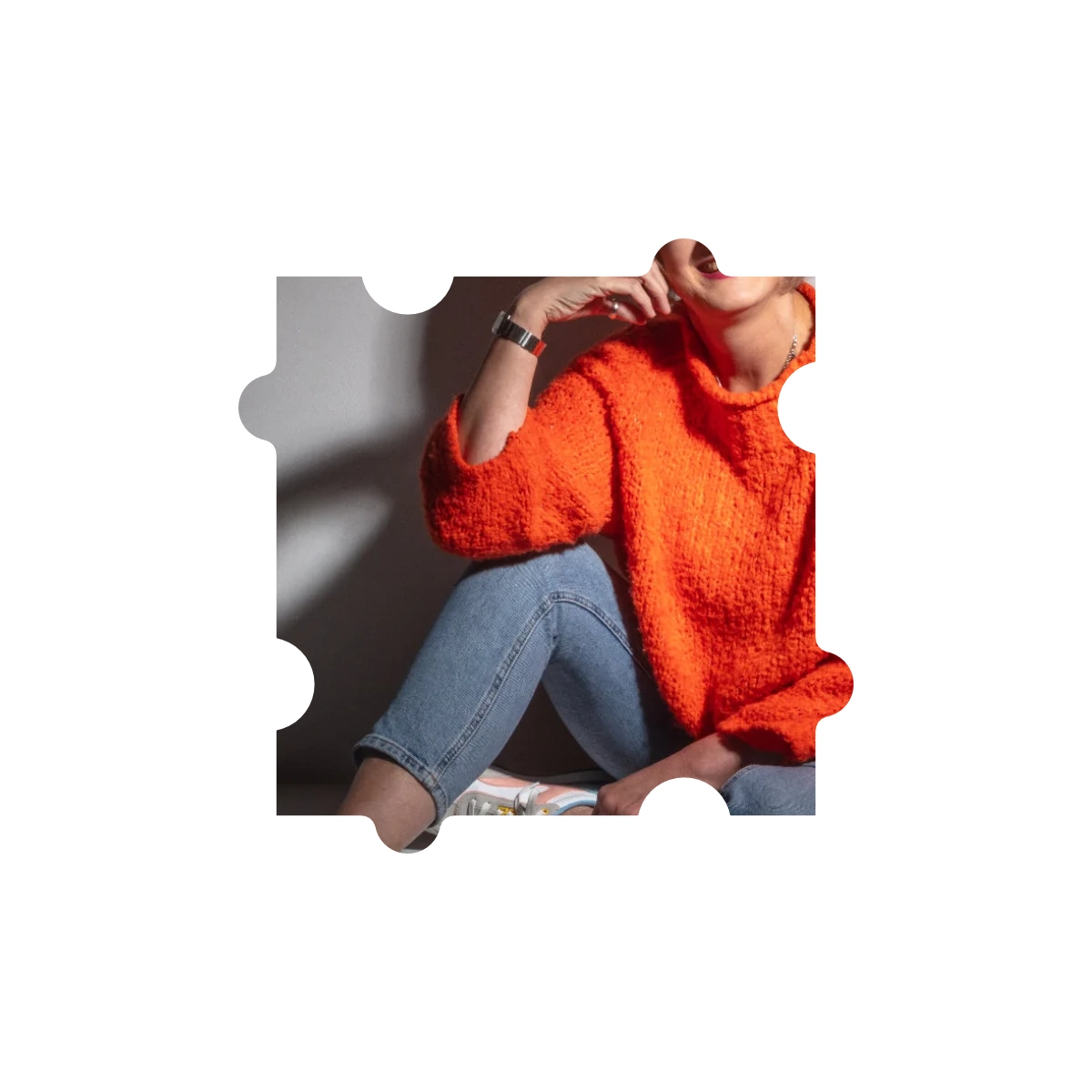Puzzleteil eines Bildes - Frau sitzt in Jeans und orangefarbenen Pullover auf dem Fußboden.