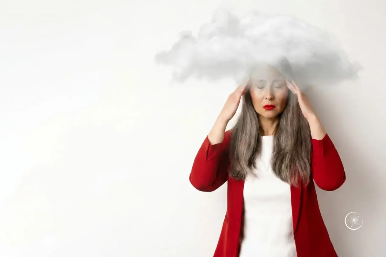Brain Fog: Frau, die sich die Schläfen massiert. Der Kopf ist eingehüllt in eine Nebelwolke.